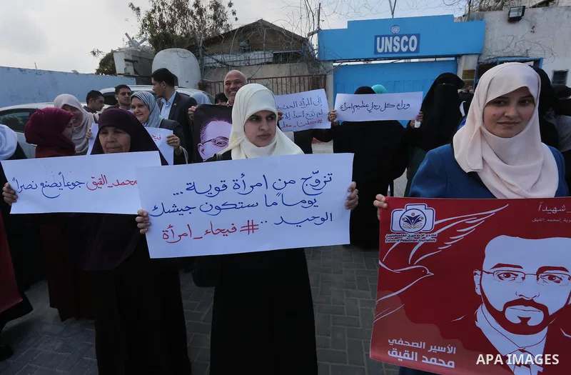 Palestinian women hold posters bearing a portrait of Palestinian journalist Mohammed al-Qiq who is imprisoned in an Israeli jail during a protest in support of his hunger strike in Gaza city on Feb. 21, 2016. Photo by Mo...