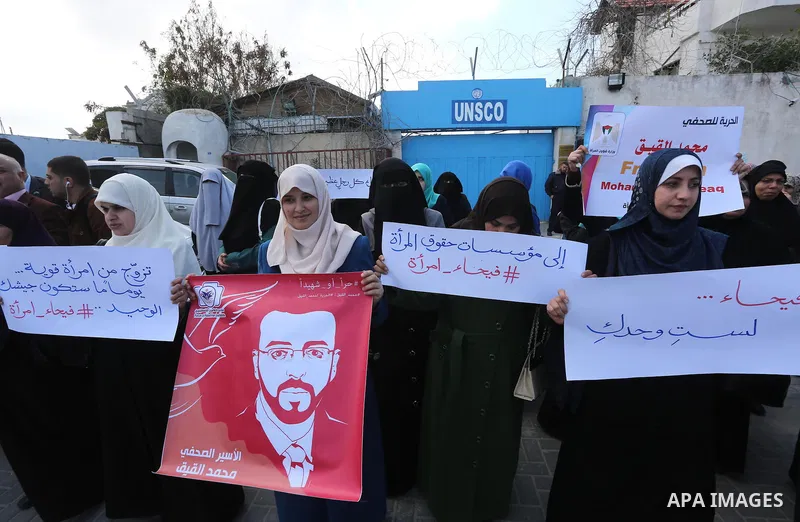 Palestinian women hold posters bearing a portrait of Palestinian journalist Mohammed al-Qiq who is imprisoned in an Israeli jail during a protest in support of his hunger strike in Gaza city on Feb. 21, 2016. Photo by Mo...