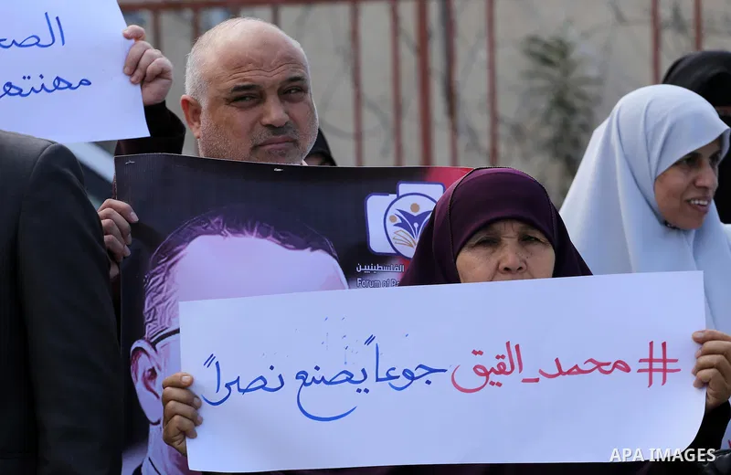 Palestinian women hold posters bearing a portrait of Palestinian journalist Mohammed al-Qiq who is imprisoned in an Israeli jail during a protest in support of his hunger strike in Gaza city on Feb. 21, 2016. Photo by Mo...