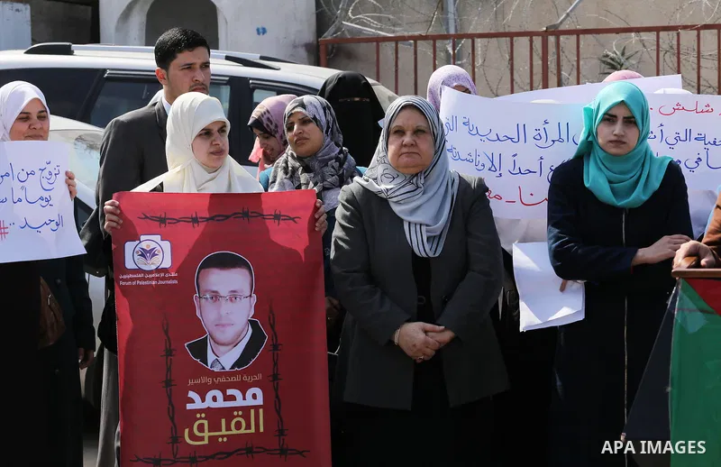 Palestinian women hold posters bearing a portrait of Palestinian journalist Mohammed al-Qiq who is imprisoned in an Israeli jail during a protest in support of his hunger strike in Gaza city on Feb. 21, 2016. Photo by Mo...