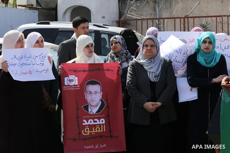 Palestinian women hold posters bearing a portrait of Palestinian journalist Mohammed al-Qiq who is imprisoned in an Israeli jail during a protest in support of his hunger strike in Gaza city on Feb. 21, 2016. Photo by Mo...
