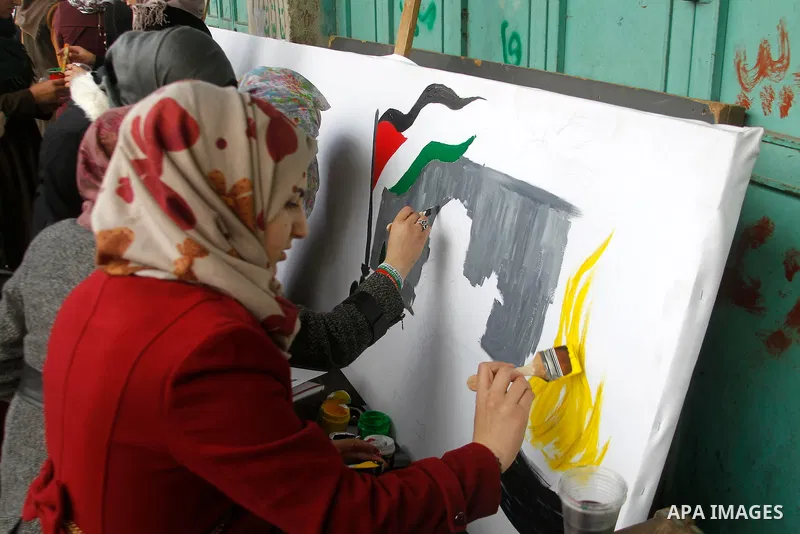 Palestinian youths paint a mural to mark the 22nd anniversary of the massacre of 29 Palestinian Muslim worshipers by Jewish extremist Baruch Goldstein at the Tomb of the Patriarchs on February 25, 1994 in the West Bank c...