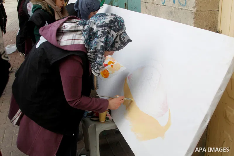 Palestinian youths paint a mural to mark the 22nd anniversary of the massacre of 29 Palestinian Muslim worshipers by Jewish extremist Baruch Goldstein at the Tomb of the Patriarchs on February 25, 1994 in the West Bank c...