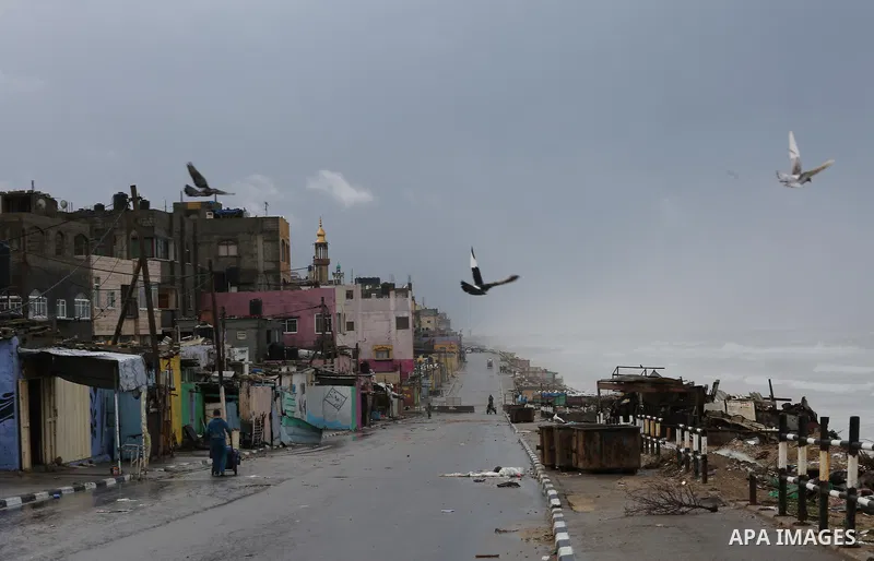 Palestinian boys walk though a flooded road on a rainy day at Shati refugee camp in Gaza city, on February 22, 2016. Photo by Mohammed Asad