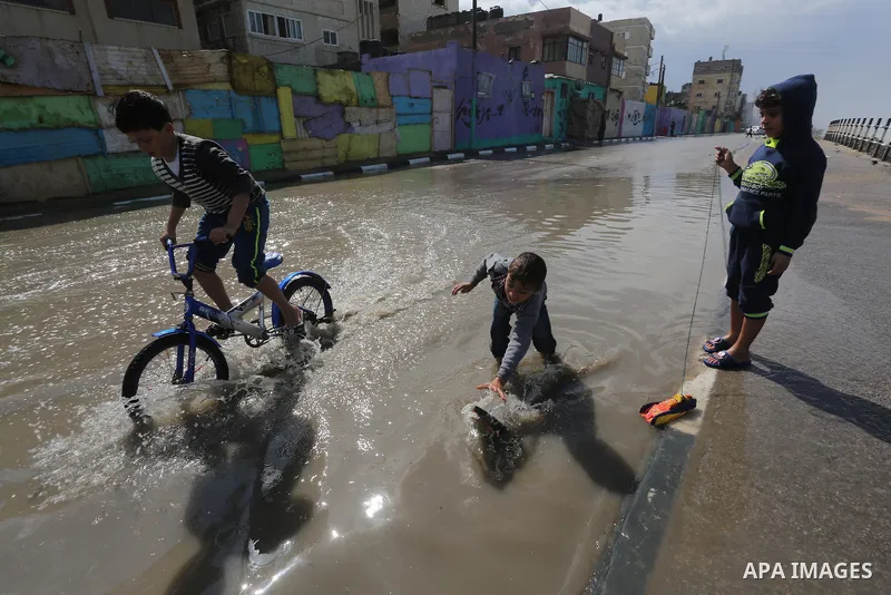 Palestinian boys play on a rainy day at Shati refugee camp in Gaza city, on February 22, 2016. Photo by Mohammed Asad