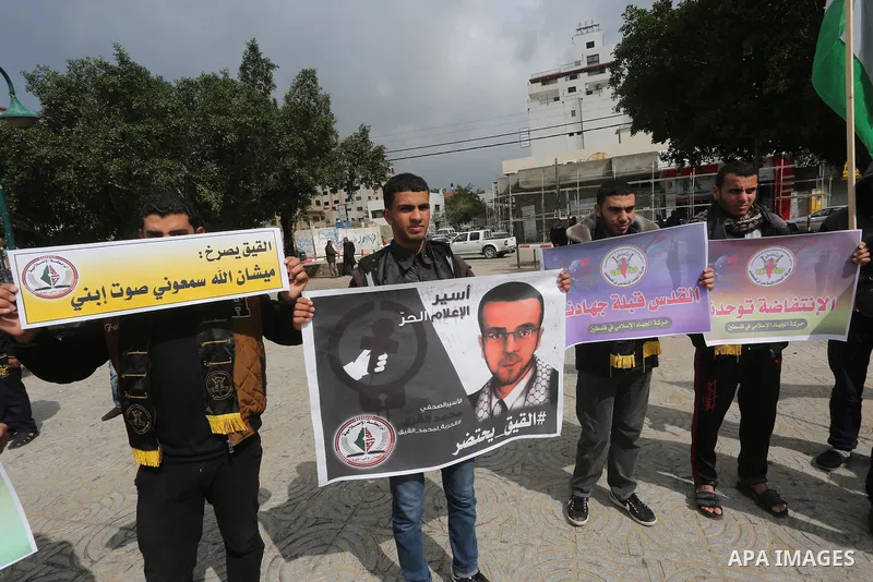 Palestinians hold posters bearing a portrait of Palestinian journalist Mohammed al-Qiq who is imprisoned in an Israeli jail during a protest in support of his hunger strike in Gaza city on Feb. 23, 2016. Photo by Mohamme...