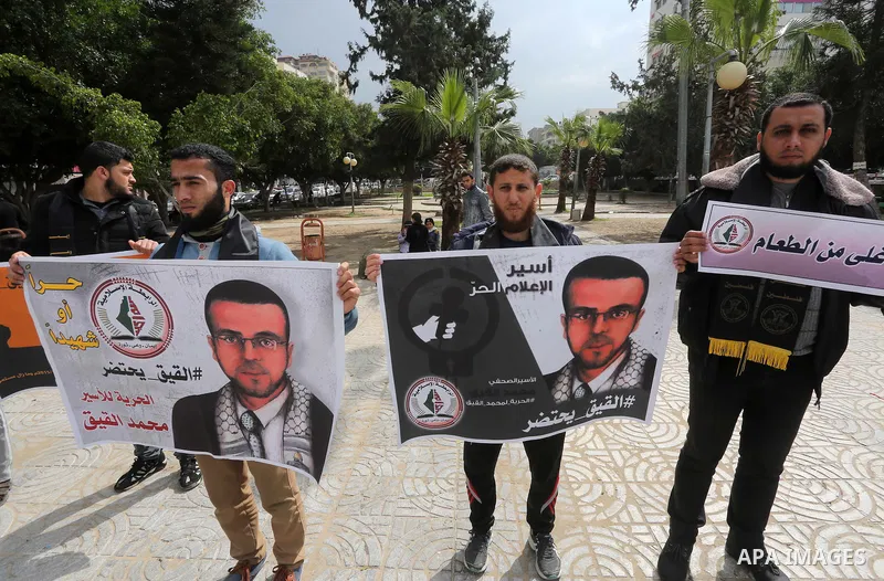 Palestinians hold posters bearing a portrait of Palestinian journalist Mohammed al-Qiq who is imprisoned in an Israeli jail during a protest in support of his hunger strike in Gaza city on Feb. 23, 2016. Photo by Mohamme...
