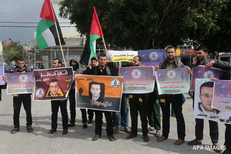 Palestinians hold posters bearing a portrait of Palestinian journalist Mohammed al-Qiq who is imprisoned in an Israeli jail during a protest in support of his hunger strike in Gaza city on Feb. 23, 2016. Photo by Mohamme...