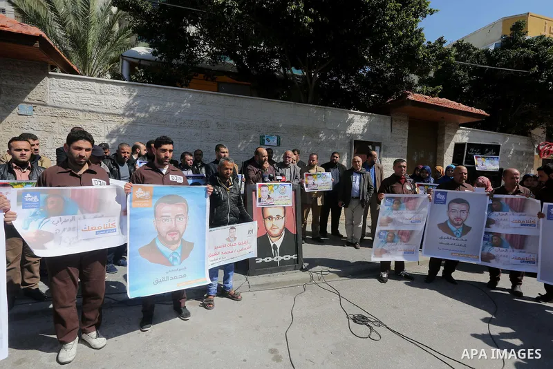 Palestinian journalists hold posters bearing a portrait of Palestinian journalist Mohammed al-Qiq who is imprisoned in an Israeli jail during a protest in support of his hunger strike in front of Red Cross office, in Gaz...