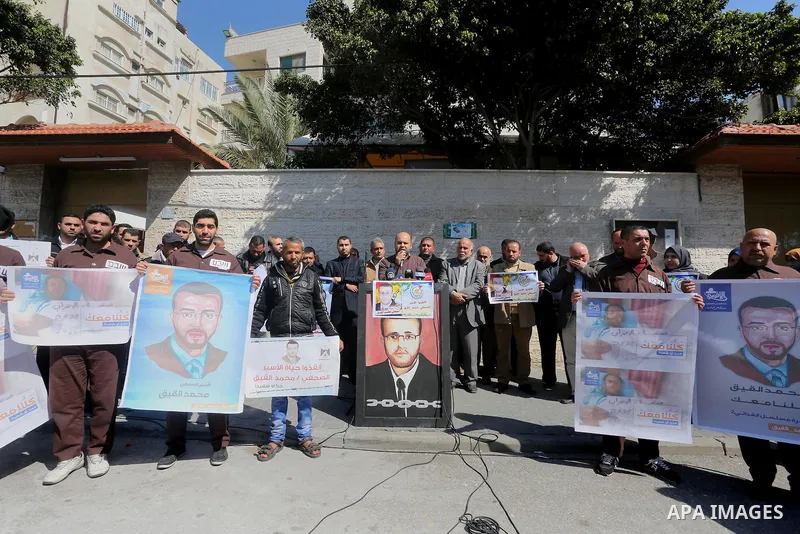 Palestinian journalists hold posters bearing a portrait of Palestinian journalist Mohammed al-Qiq who is imprisoned in an Israeli jail during a protest in support of his hunger strike in front of Red Cross office, in Gaz...