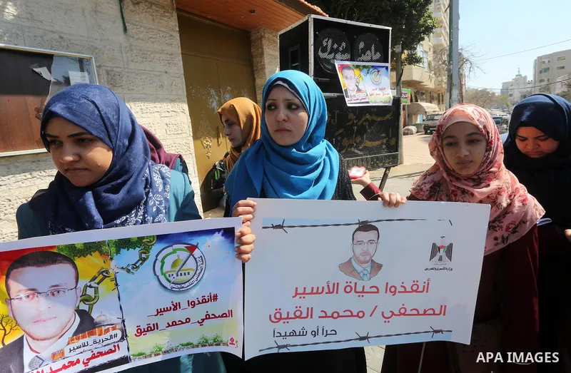 Palestinian journalists hold posters bearing a portrait of Palestinian journalist Mohammed al-Qiq who is imprisoned in an Israeli jail during a protest in support of his hunger strike in front of Red Cross office, in Gaz...