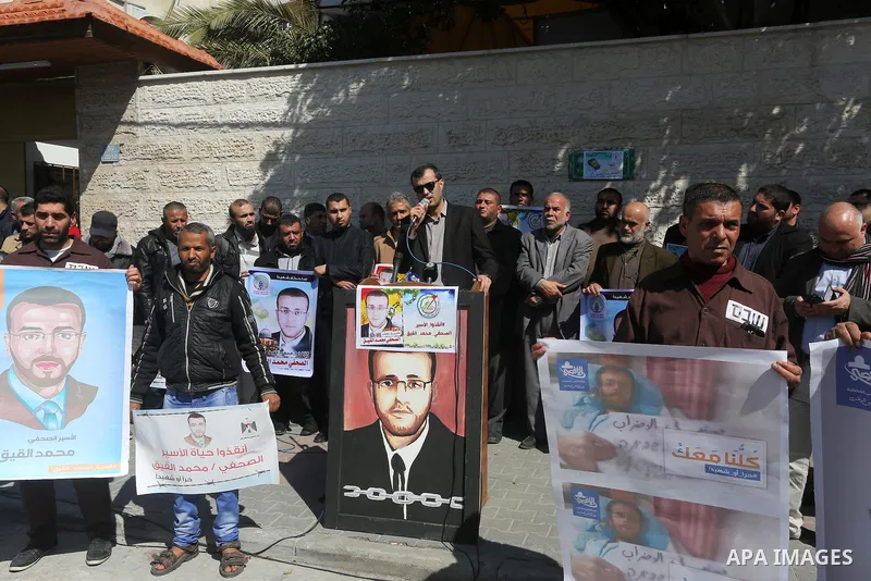 Palestinian journalists hold posters bearing a portrait of Palestinian journalist Mohammed al-Qiq who is imprisoned in an Israeli jail during a protest in support of his hunger strike in front of Red Cross office, in Gaz...