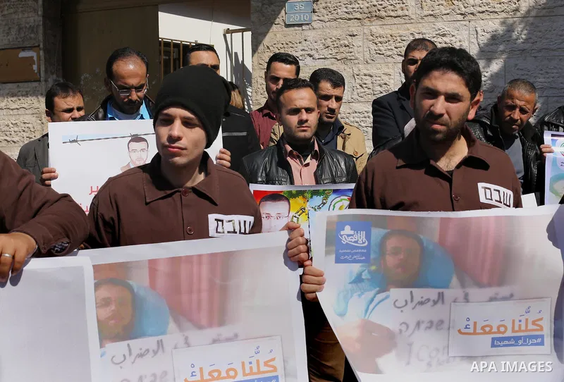 Palestinian journalists hold posters bearing a portrait of Palestinian journalist Mohammed al-Qiq who is imprisoned in an Israeli jail during a protest in support of his hunger strike in front of Red Cross office, in Gaz...