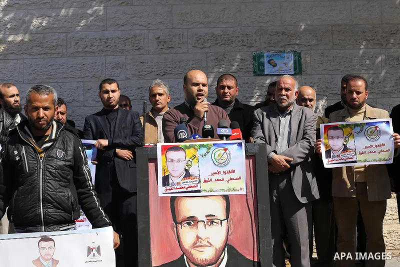 Palestinian journalists hold posters bearing a portrait of Palestinian journalist Mohammed al-Qiq who is imprisoned in an Israeli jail during a protest in support of his hunger strike in front of Red Cross office, in Gaz...