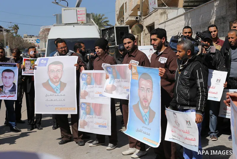 Palestinian journalists hold posters bearing a portrait of Palestinian journalist Mohammed al-Qiq who is imprisoned in an Israeli jail during a protest in support of his hunger strike in front of Red Cross office, in Gaz...