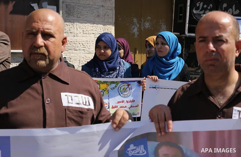 Palestinian journalists hold posters bearing a portrait of Palestinian journalist Mohammed al-Qiq who is imprisoned in an Israeli jail during a protest in support of his hunger strike in front of Red Cross office, in Gaz...