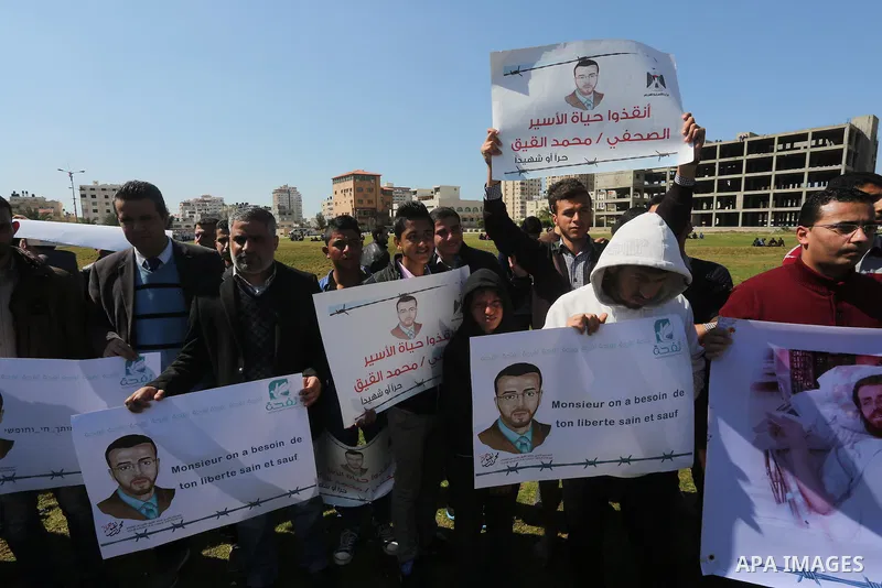 Palestinian students hold posters bearing a portrait of Palestinian journalist Mohammed al-Qiq who is imprisoned in an Israeli jail during a protest in support of his hunger strike, in Gaza city, on Feb. 24, 2016. Photo...