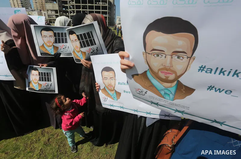 Palestinian students hold posters bearing a portrait of Palestinian journalist Mohammed al-Qiq who is imprisoned in an Israeli jail during a protest in support of his hunger strike, in Gaza city, on Feb. 24, 2016. Photo...