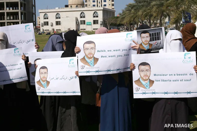 Palestinian students hold posters bearing a portrait of Palestinian journalist Mohammed al-Qiq who is imprisoned in an Israeli jail during a protest in support of his hunger strike, in Gaza city, on Feb. 24, 2016. Photo...
