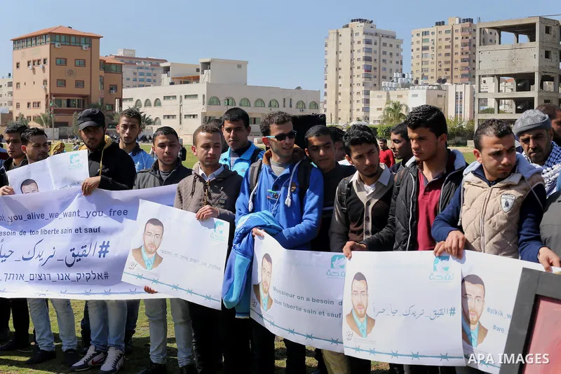 Palestinian students hold posters bearing a portrait of Palestinian journalist Mohammed al-Qiq who is imprisoned in an Israeli jail during a protest in support of his hunger strike, in Gaza city, on Feb. 24, 2016. Photo...