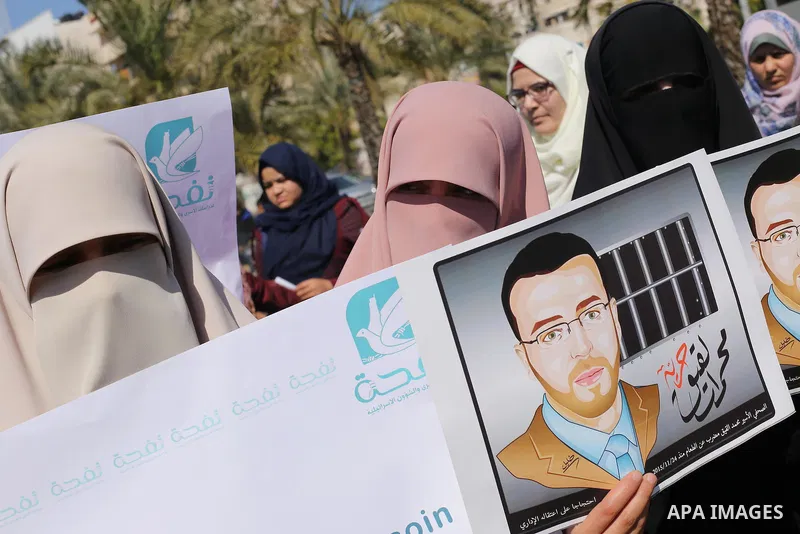 Palestinian students hold posters bearing a portrait of Palestinian journalist Mohammed al-Qiq who is imprisoned in an Israeli jail during a protest in support of his hunger strike, in Gaza city, on Feb. 24, 2016. Photo...