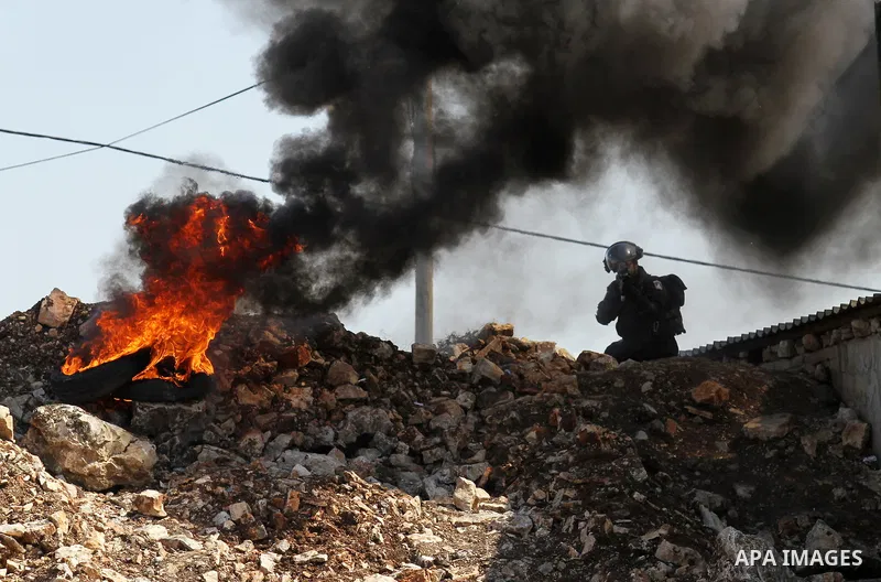 A member of Israeli security forces aims his weapon at Palestinian protesters during clashes following a protest against the expropriation of Palestinian land by Israel in the West Bank village of Kafr Qaddum, near the n...