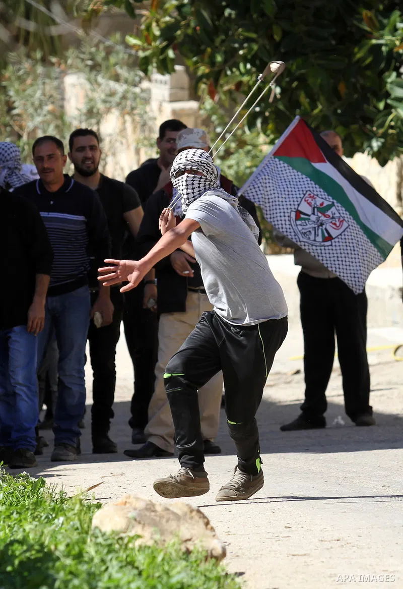 A Palestinian protester uses a slingshot to hurl stones toward Israeli security forces during clashes following a protest against the expropriation of Palestinian land by Israel in the West Bank village of Kafr Qaddum, n...