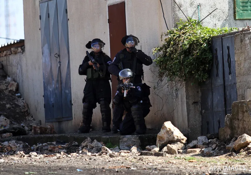 A member of Israeli security forces aims his weapon at Palestinian protesters during clashes following a protest against the expropriation of Palestinian land by Israel in the West Bank village of Kafr Qaddum, near the n...