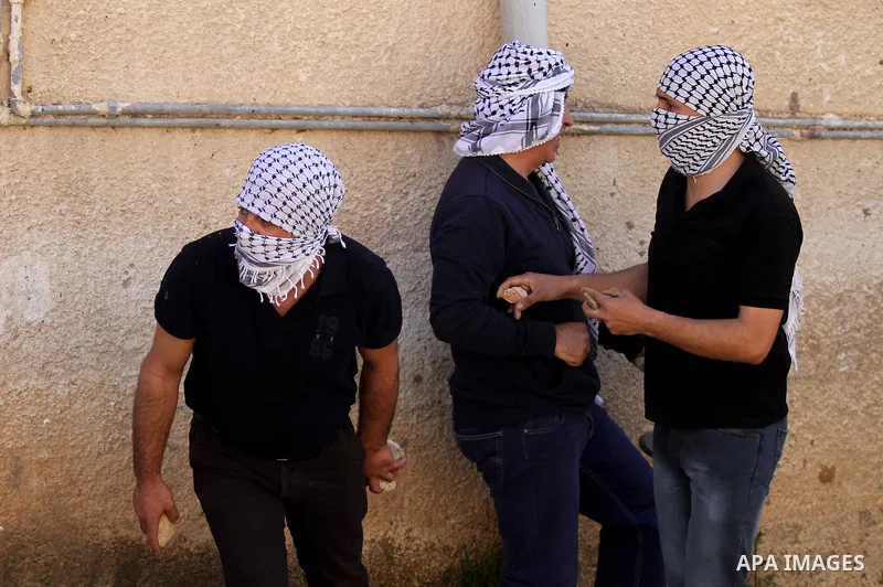 Palestinian protesters hurl stones toward Israeli security forces during clashes following a protest against the expropriation of Palestinian land by Israel in the West Bank village of Kafr Qaddum, near the northern city...