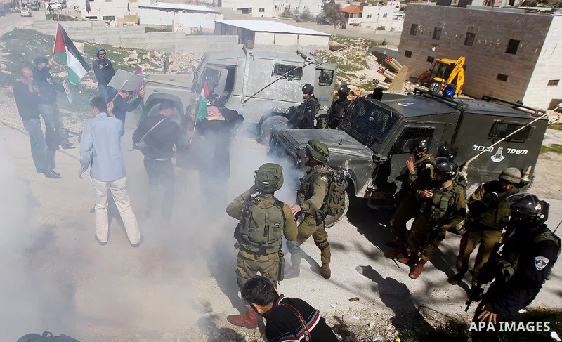 Palestinian protesters run for cover from as Israeli troops fire sound and tear gas grenades during a demonstration against the closure of Shuhada street to Palestinians, on the 22nd anniversary of the closure, in the We...
