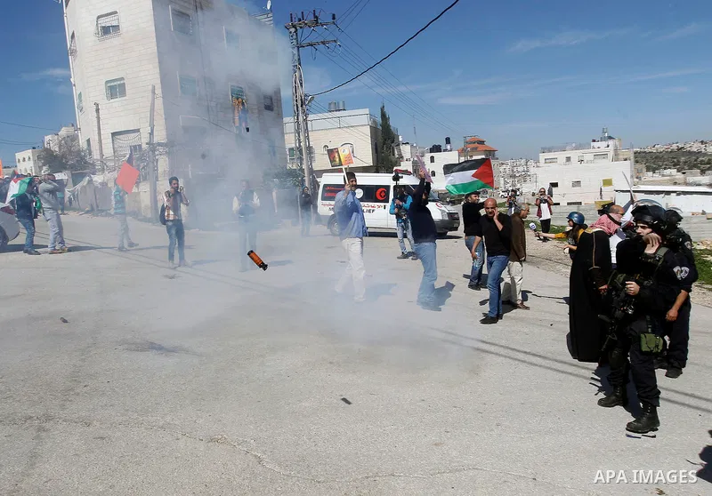 Palestinian protesters run for cover from as Israeli troops fire sound and tear gas grenades during a demonstration against the closure of Shuhada street to Palestinians, on the 22nd anniversary of the closure, in the We...