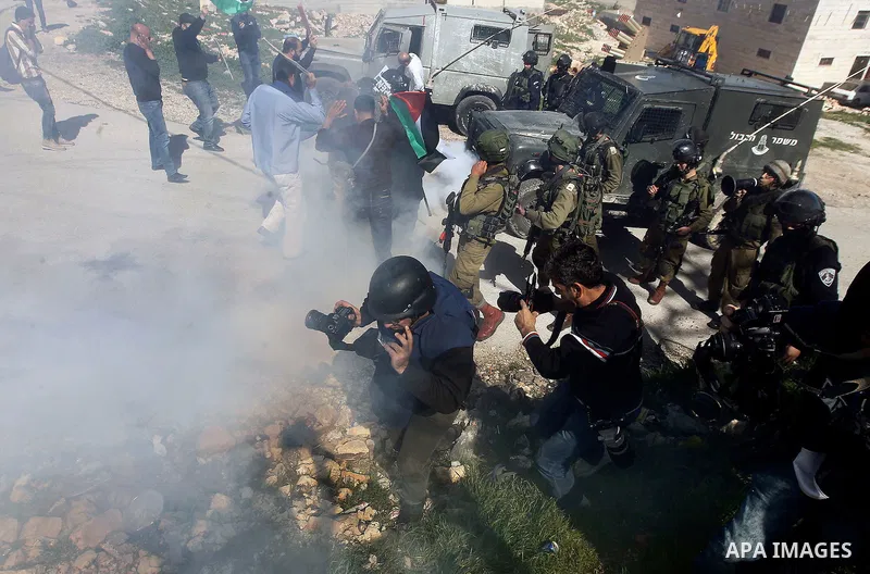 Palestinian protesters run for cover from as Israeli troops fire sound and tear gas grenades during a demonstration against the closure of Shuhada street to Palestinians, on the 22nd anniversary of the closure, in the We...