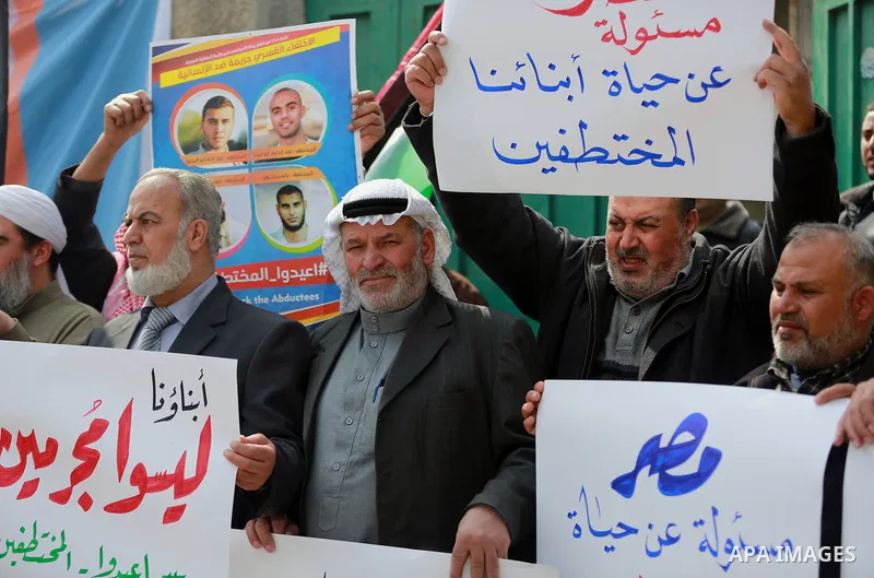 Relatives of four Palestinian men abducted by unidentified masked gunmen on August 19, hold their relatives' pictures during a protest demanding for their return, in front of the Egyptian embassy, in Gaza city, on Februa...