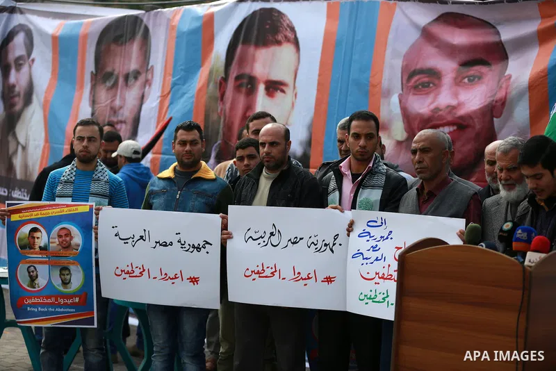 Relatives of four Palestinian men abducted by unidentified masked gunmen on August 19, hold their relatives' pictures during a protest demanding for their return, in front of the Egyptian embassy, in Gaza city, on Februa...