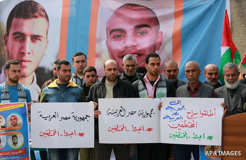 Relatives of four Palestinian men abducted by unidentified masked gunmen on August 19, hold their relatives' pictures during a protest demanding for their return, in front of the Egyptian embassy, in Gaza city, on Februa...
