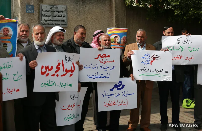 Relatives of four Palestinian men abducted by unidentified masked gunmen on August 19, hold their relatives' pictures during a protest demanding for their return, in front of the Egyptian embassy, in Gaza city, on Februa...