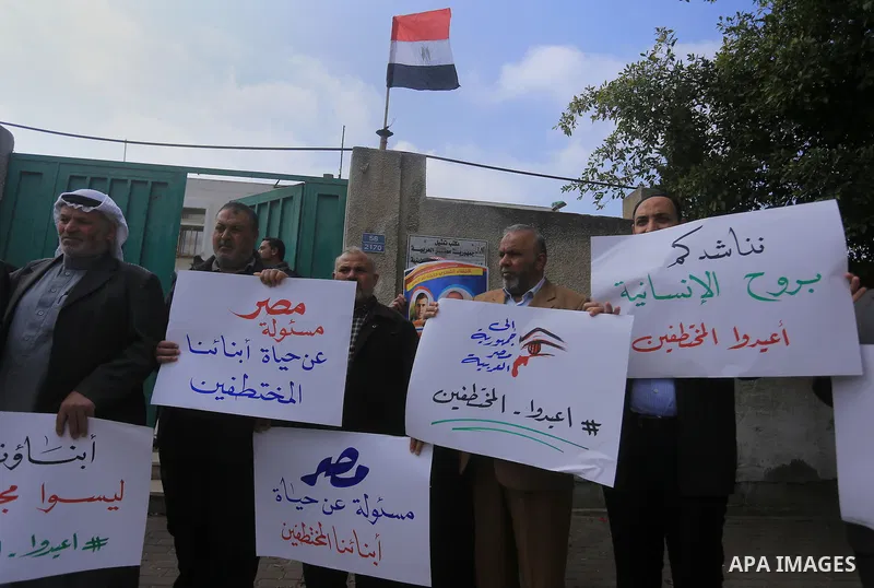 Relatives of four Palestinian men abducted by unidentified masked gunmen on August 19, hold their relatives' pictures during a protest demanding for their return, in front of the Egyptian embassy, in Gaza city, on Februa...