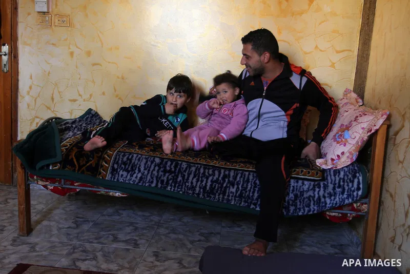 Palestinian Wael al-Namla and his son Sharif, who were both injured during the 50-day war between Israel and Hamas militants in the summer of 2014, play in on the bed at their house on Feb. 28, 2016 in Rafah in the south...