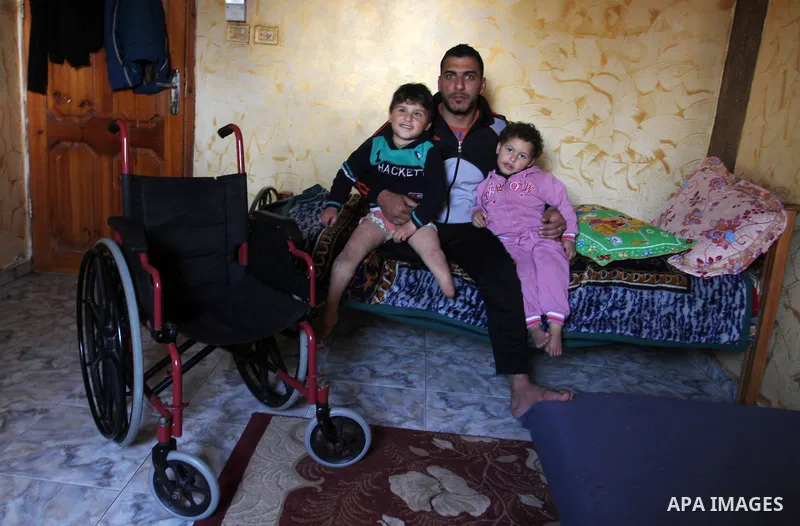 Palestinian Wael al-Namla and his son Sharif, who were both injured during the 50-day war between Israel and Hamas militants in the summer of 2014, sit in on the bed at their house on Feb. 28, 2016 in Rafah in the southe...