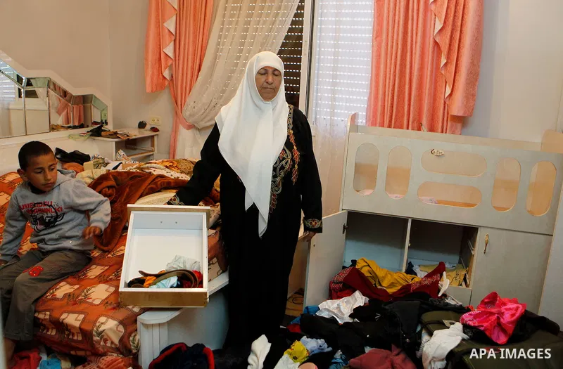 A Palestinian woman checks her belongings after a raid conducted by the Israeli army on some Palestinian houses in the West Bank city of Hebron, 29 February 2016. The Israeli army said it had arrested 16 Palestinians in...