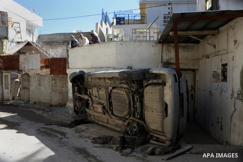 Palestinians look out of their house as a Palestinian car, that was damaged during clashes with Israeli troops, is seen at Qalandia refugee camp near the West Bank city of Ramallah March 1, 2016. Israeli forces shot dead...
