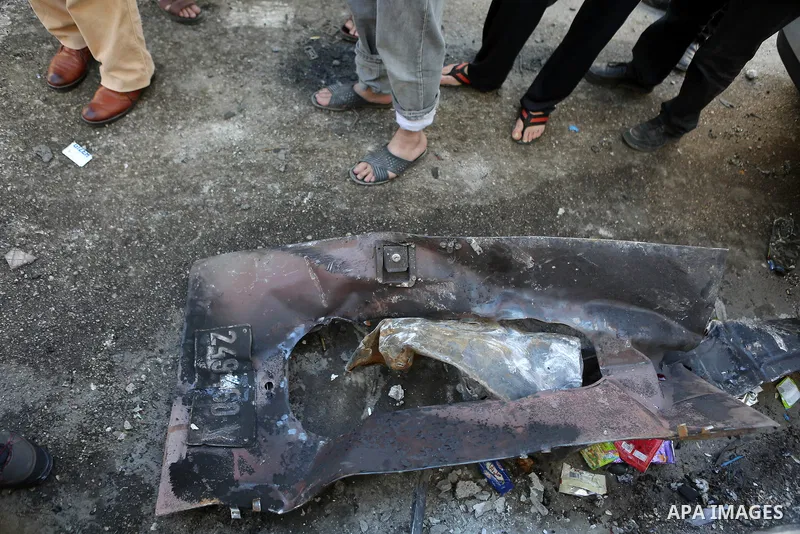 Palestinian men stand next to the charred remains of an Israeli military vehicle at the Qalandya Refugee camp following clashes between Palestinian youths and Israeli security forces on March 1, 2016. Two Israeli soldier...