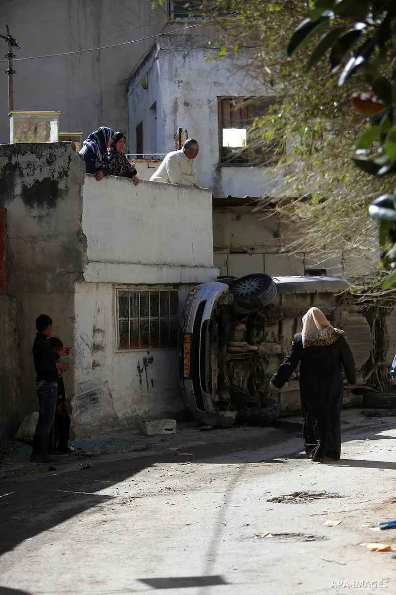 Palestinians look out of their house as a Palestinian car, that was damaged during clashes with Israeli troops, is seen at Qalandia refugee camp near the West Bank city of Ramallah March 1, 2016. Israeli forces shot dead...