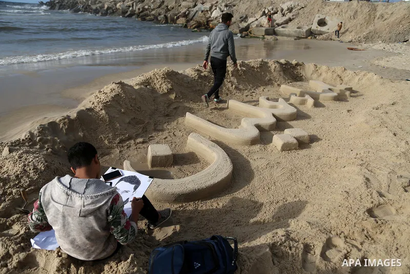 A Palestinian artist paints a portrait of Bahaa Alian, who was killed by Israeli security forces during a reading human chain at the beach of Gaza city on March 03, 2016. Photo by Mohammed Asad