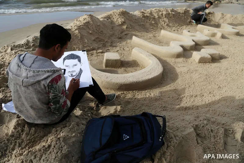 A Palestinian artist paints a portrait of Bahaa Alian, who was killed by Israeli security forces during a reading human chain at the beach of Gaza city on March 03, 2016. Photo by Mohammed Asad