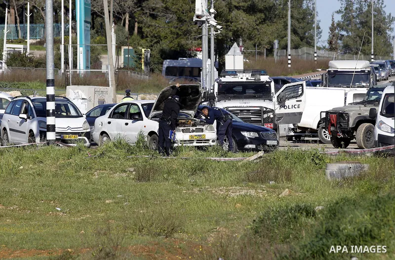Israeli security forces inspect a car used by a Palestinian woman who, the Israeli military said, rammed it into an Israeli soldier before she was shot dead by the Israeli troops, at a main junction near the Israeli sett...