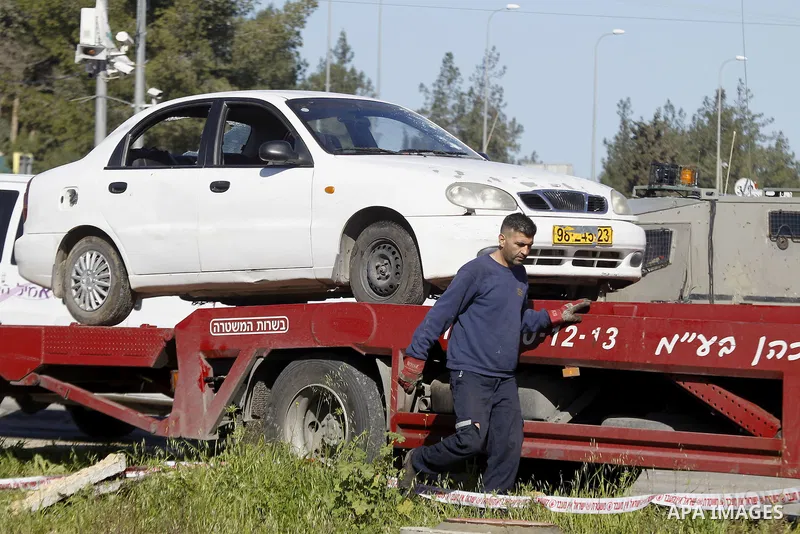 An Israeli policeman stands guard during the removal of a car used by a Palestinian woman who, the Israeli military said, rammed it into an Israeli soldier before she was shot dead by the Israeli troops, at a main juncti...