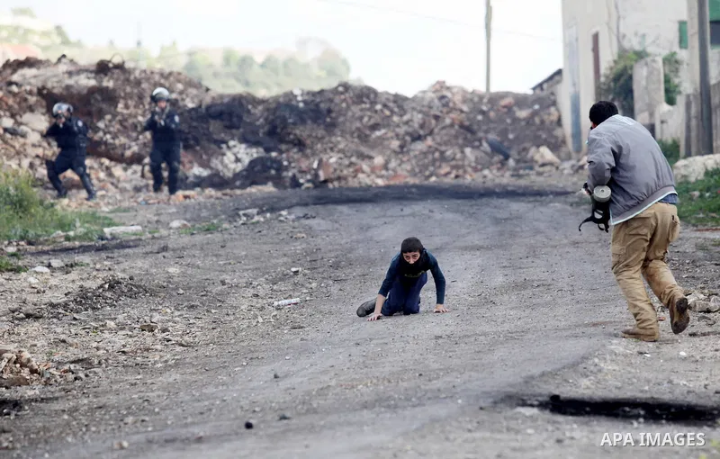A Palestinian man rushes towards a boy who was injured during clashes with Israeli security forces following a demonstration against the expropriation of Palestinian land by Israel, in the village of Kfar Qaddum, near Na...