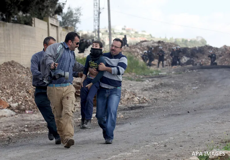 A Palestinian man carries a boy after he was injured during clashes with Israeli security forces following a demonstration against the expropriation of Palestinian land by Israel, in the village of Kfar Qaddum, near Nabl...
