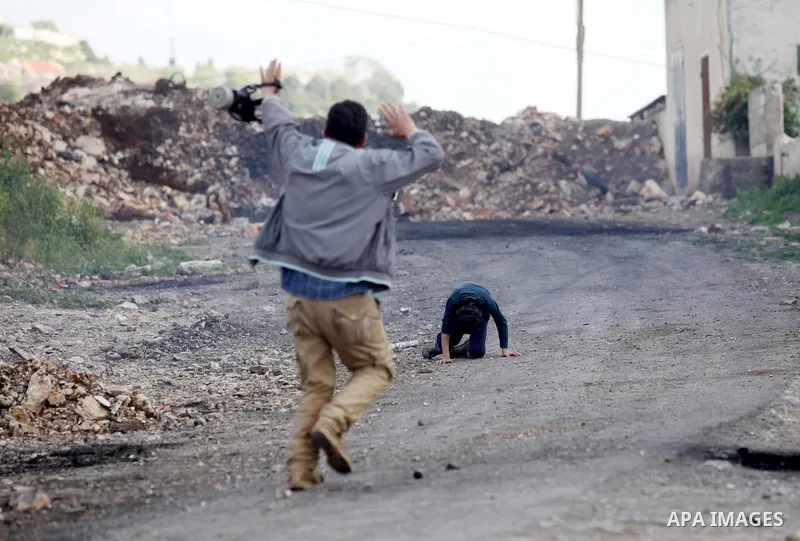 A Palestinian man rushes towards a boy who was injured during clashes with Israeli security forces following a demonstration against the expropriation of Palestinian land by Israel, in the village of Kfar Qaddum, near Na...